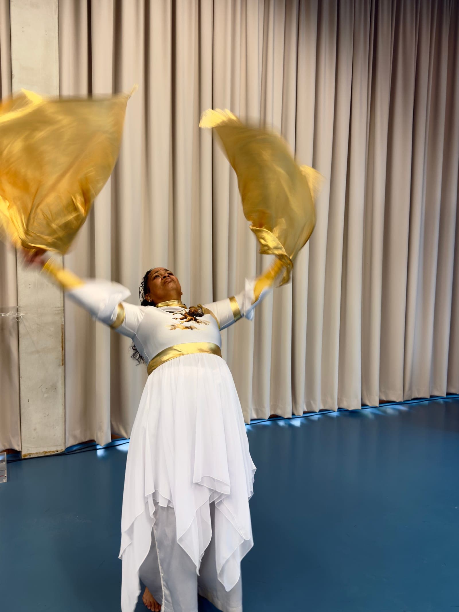 A dancer in white lifting gold worship flags