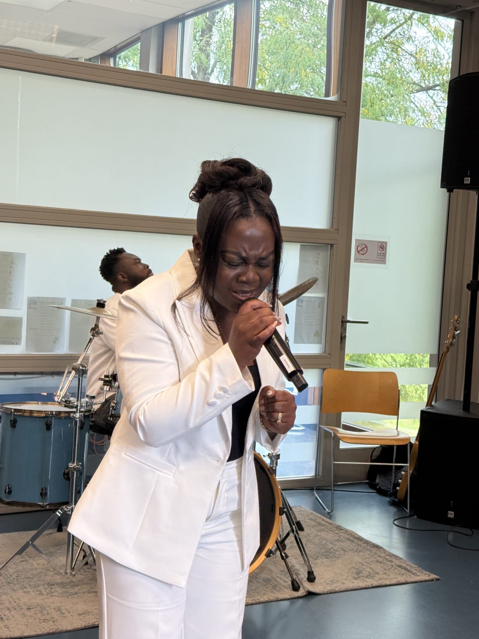 A worship leader singing into a microphone beside the drum kit